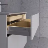 Klassisesta tyylistä inspiroitunut pieni kylpyhuone, jossa on oliivinvihreä turhamaisuusyksikkö ja yläkaappi, kaunis neliönmuotoinen peili, kalanruotolattia ja tapetti antavat ylellisen ja hienostuneen ilmeen.