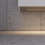 Tyylikäs kylpyhuone inspiraatio beige pesuallaskaapilla, jossa on sisälaatikko, yläkaappi, avoin hylly, soikea peili valaistuksella, yhteensopivat riippuvalaisimet, hylly peilin alla ja seinään kiinnitetty WC. Vaaleat, pitkät laatat seinillä