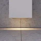 Suuri kylpyhuone inspiroi harmaalla turhamaisuuskaapilla, jossa on integroitu kahva, tyylikäs sivulle asennettu pesuallas, neliön muotoinen peili pyöristetyillä kulmilla, betonin näköiset seinät ja raaka-aineet urbaanin ilmeen luomiseksi.