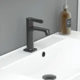 Tyylikäs kylpyhuone inspiraatio beige pesuallaskaapilla, jossa on sisälaatikko, yläkaappi, avoin hylly, soikea peili valaistuksella, yhteensopivat riippuvalaisimet, hylly peilin alla ja seinään kiinnitetty WC. Vaaleat, pitkät laatat seinillä