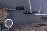 Suuri kylpyhuone inspiroi harmaalla turhamaisuuskaapilla, jossa on integroitu kahva, tyylikäs sivulle asennettu pesuallas, neliön muotoinen peili pyöristetyillä kulmilla, betonin näköiset seinät ja raaka-aineet urbaanin ilmeen luomiseksi