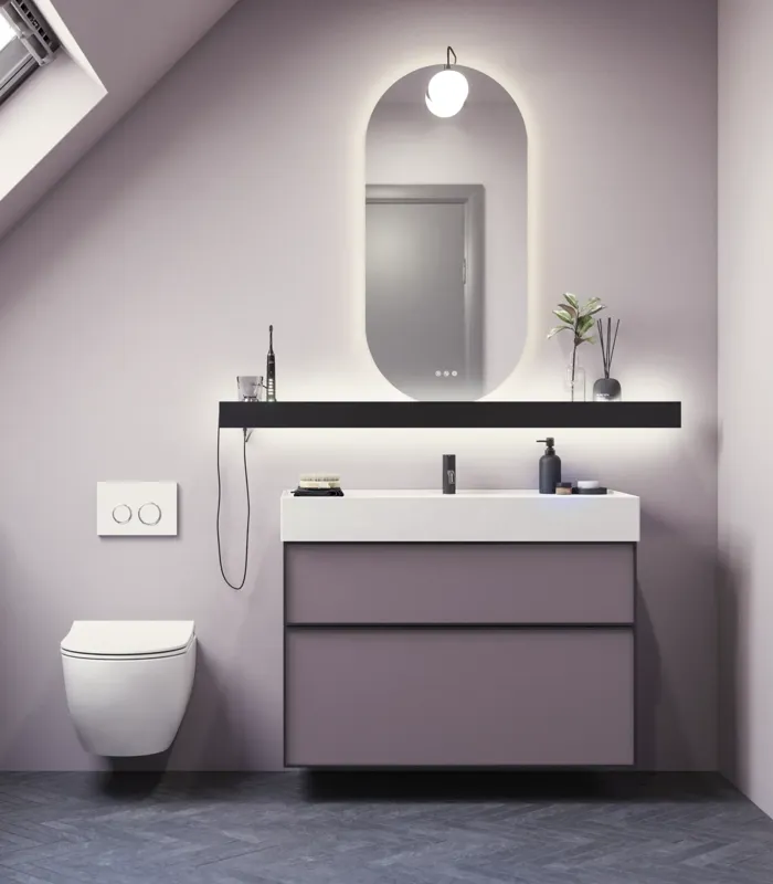 Kylpyhuone, jossa on vinot seinät, inspiraatio, kylpyhuonekalusteet liilaa, elegantit kehysovet, kaunis soikea peili lampulla, kaunis ja käytännöllinen hylly, liilaksi maalattu seinä ja harmaa kalanruotolattia, jotka antavat elegantin ja modernin ilmeen.