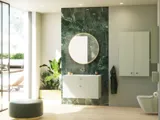 Tyylikäs ja ylellinen kylpyhuone, jossa on pehmeitä vihreitä sävyjä, suuri elegantti pyöreä peili ja moderni, hienostunut vihreä wc-istuin