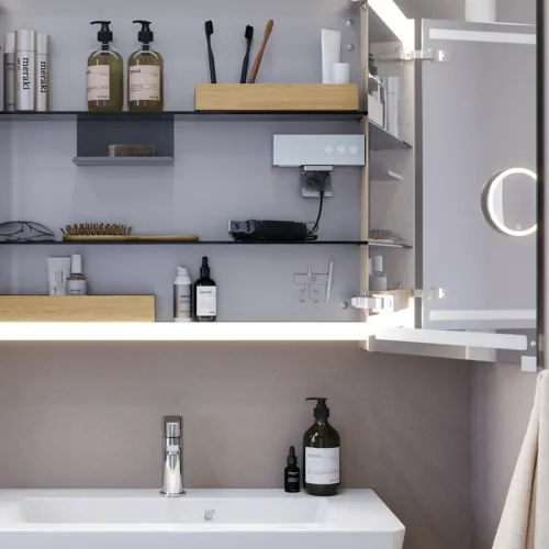Pienen kylpyhuoneen inspiraatio, beige erikoisvärinen allaskaappi ja yläkaappi wc yläpuolella, tyylikäs peilikaappi integroidulla valolla, vaaleat värit ja valkoinen verho luovat romanttisen ja naisellisen tunnelman.