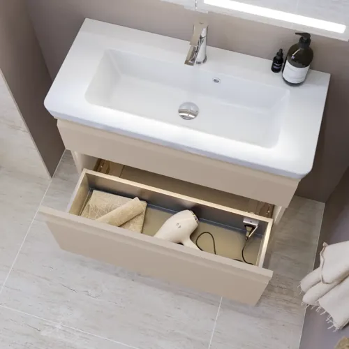 Pienen kylpyhuoneen inspiraatio, beige erikoisvärinen allaskaappi ja yläkaappi wc yläpuolella, tyylikäs peilikaappi integroidulla valolla, vaaleat värit ja valkoinen verho luovat romanttisen ja naisellisen tunnelman.