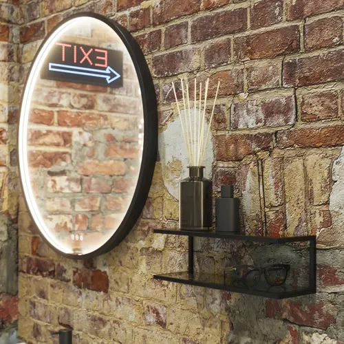 Raaka ja moderni kylpyhuone urbaaniin tyyliin. Kauniit allaskaapit ja pyöreät peilit mustilla reunoilla