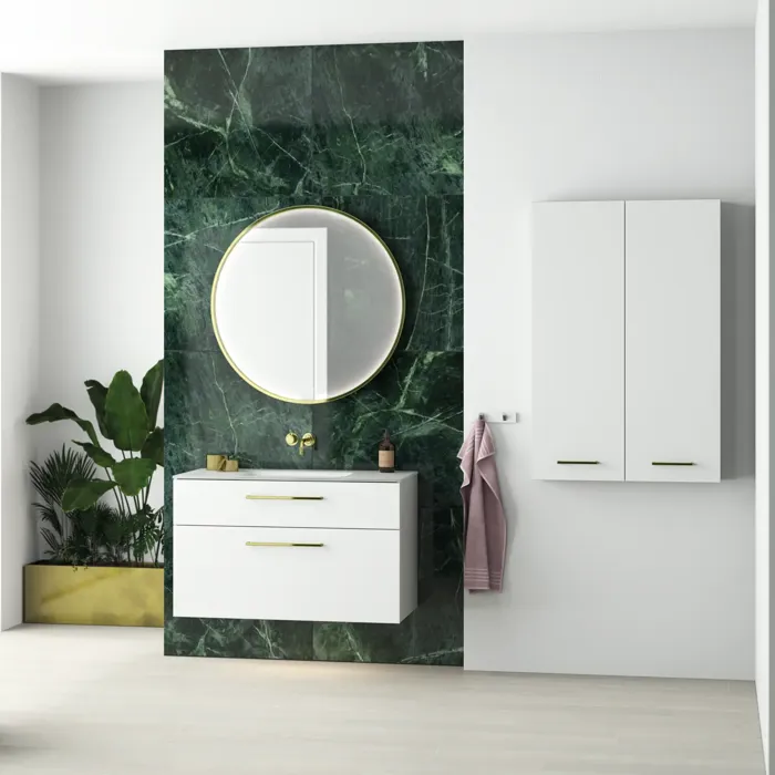 Tyylikäs ja ylellinen kylpyhuone, jossa on tummanvihreä marmoriseinä, suuri elegantti pyöreä peili ja modernit valkoiset kylpyhuonekalusteet.
