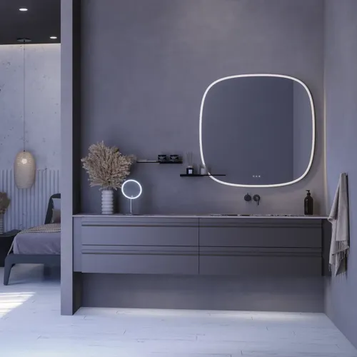 Suuri kylpyhuone inspiroi harmaalla turhamaisuuskaapilla, jossa on integroitu kahva, tyylikäs sivulle asennettu pesuallas, neliön muotoinen peili pyöristetyillä kulmilla, betonin näköiset seinät ja raaka-aineet urbaanin ilmeen luomiseksi.