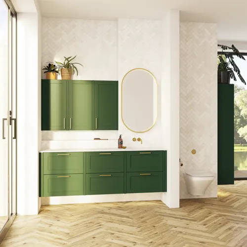 Suuri vihreä kylpyhuone, jossa allaskaappi, soikea peili kultaisella reunalla ja kauniit kehykselliset ovet